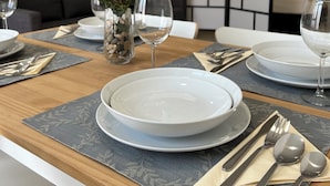 A dining table set with plates, cutlery, and a vase with flowers.