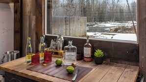 A wooden table with bottles of tequila and other beverages, a knife, and a potted plant. - River's Ranch - Riverfront with Hot Tub & Theater (Kalispell)