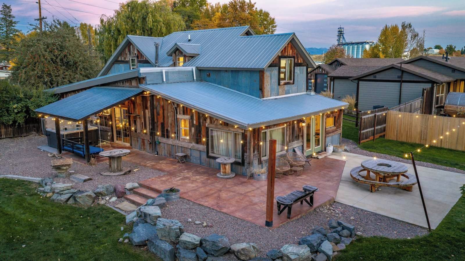 A rustic cabin with a covered patio, outdoor seating, and a stone pathway.