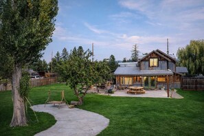 A rustic cabin with a large deck, outdoor seating, and a well-maintained yard.