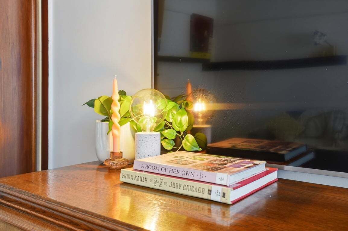 Ein Holztisch mit Büchern, einer Kerze und einer Pflanze.