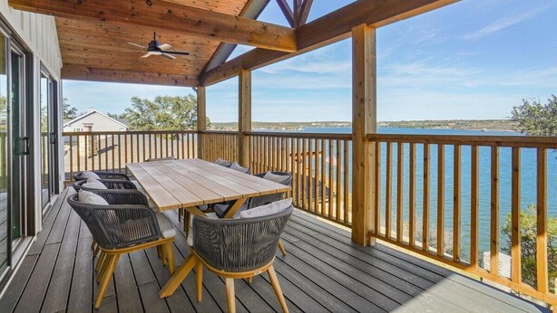 Een houten terras met een tafel en stoelen, met uitzicht op een waterpartij.