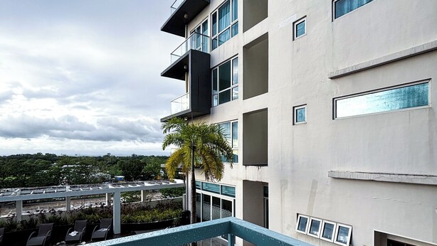A modern building with a pool area, including a blue-tiled pool and lounge chairs.