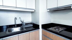 A modern kitchen with white cabinets, a stainless steel sink, and a black countertop.