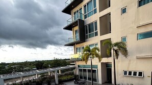A modern building with a swimming pool, outdoor seating, and a view of the surrounding area.