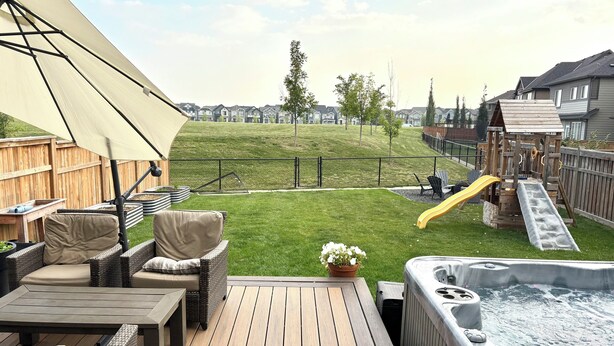 A deck with outdoor furniture, a hot tub, and a slide. - Spacious 5BR Retreat w/ Hot Tub, Fire Pit, Gym & Movie Room (Calgary)
