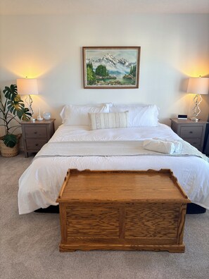 A neatly made bed with white linens, a wooden bench in front, and two bedside tables with lamps. - Spacious 5BR Retreat w/ Hot Tub, Fire Pit, Gym & Movie Room (Calgary)