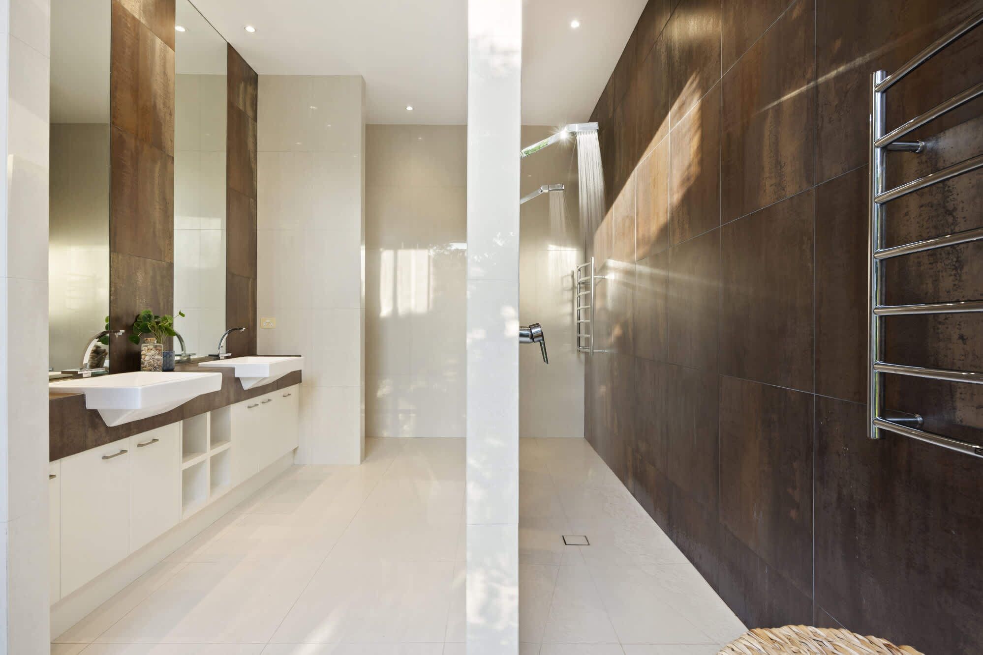 A modern bathroom with two sinks, a large mirror, and a shower area.