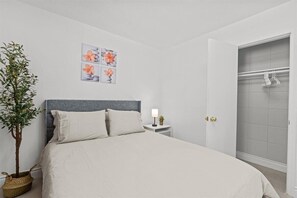 A bedroom with a bed, a nightstand, a potted plant, and a wall-mounted artwork. - Charming 1-bedroom bungalow with AC in pleasant Tustin (Tustin)
