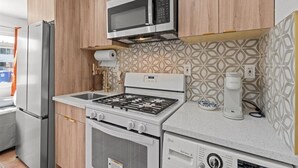 Moderni keittiö, jossa on sisäänrakennettu mikroaaltouuni, kaasuliesi, uuni ja kahvinkeitin.