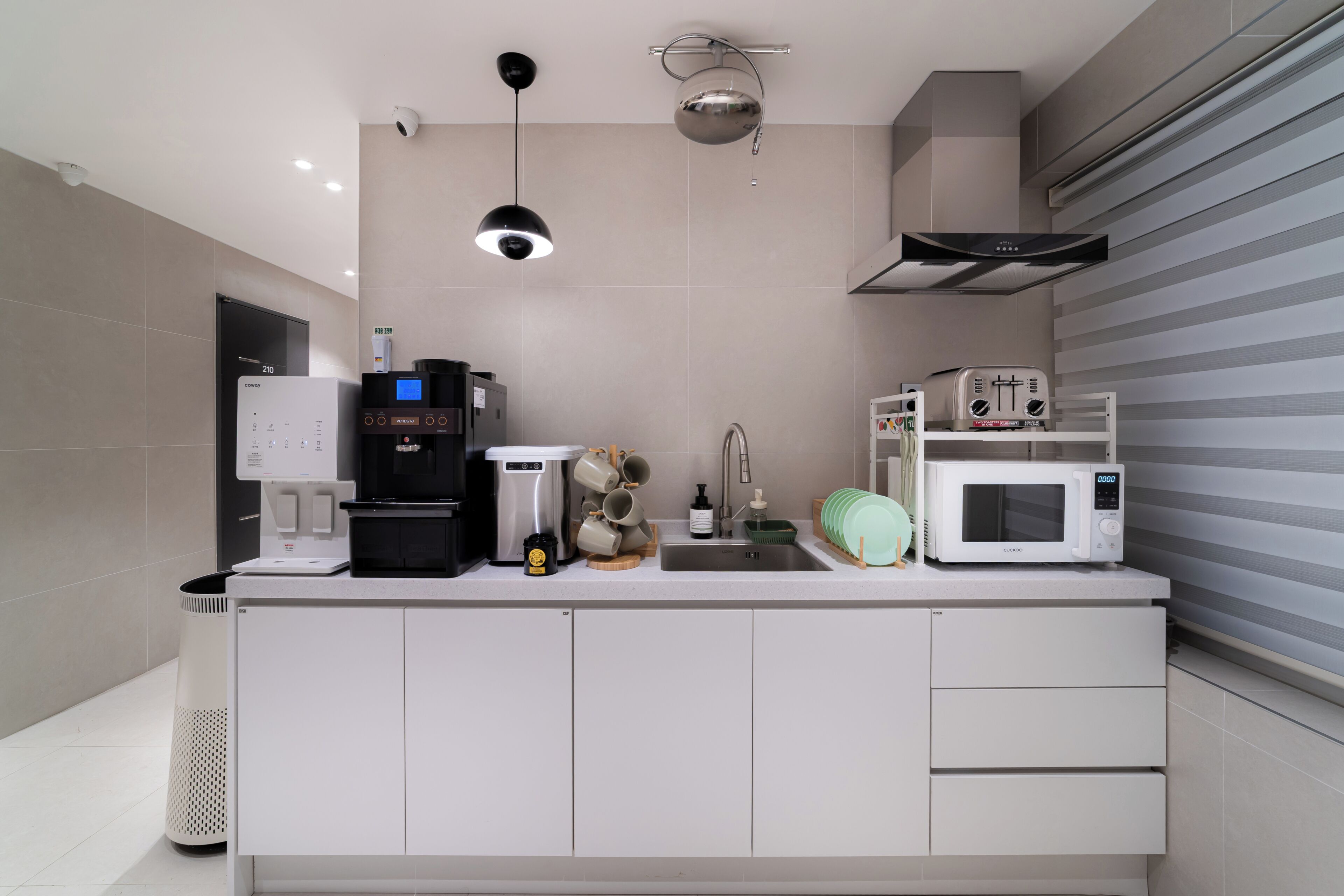 A modern kitchen with a coffee machine, microwave, and a sink.