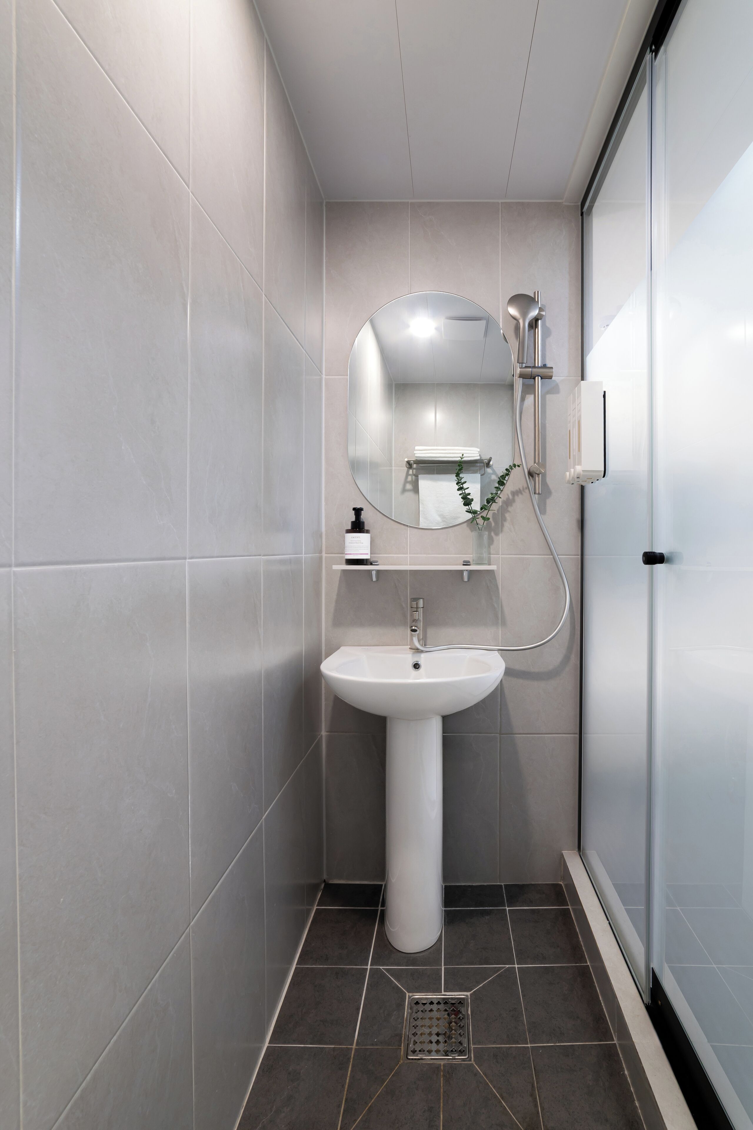 A modern bathroom with a white sink, a mirror, and a shower.