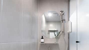 A modern bathroom with a white sink, a mirror, and a shower.