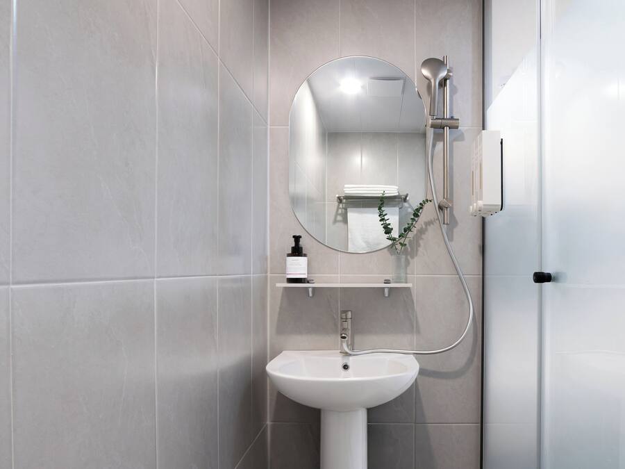 A modern bathroom with a white sink, a mirror, and a shower.