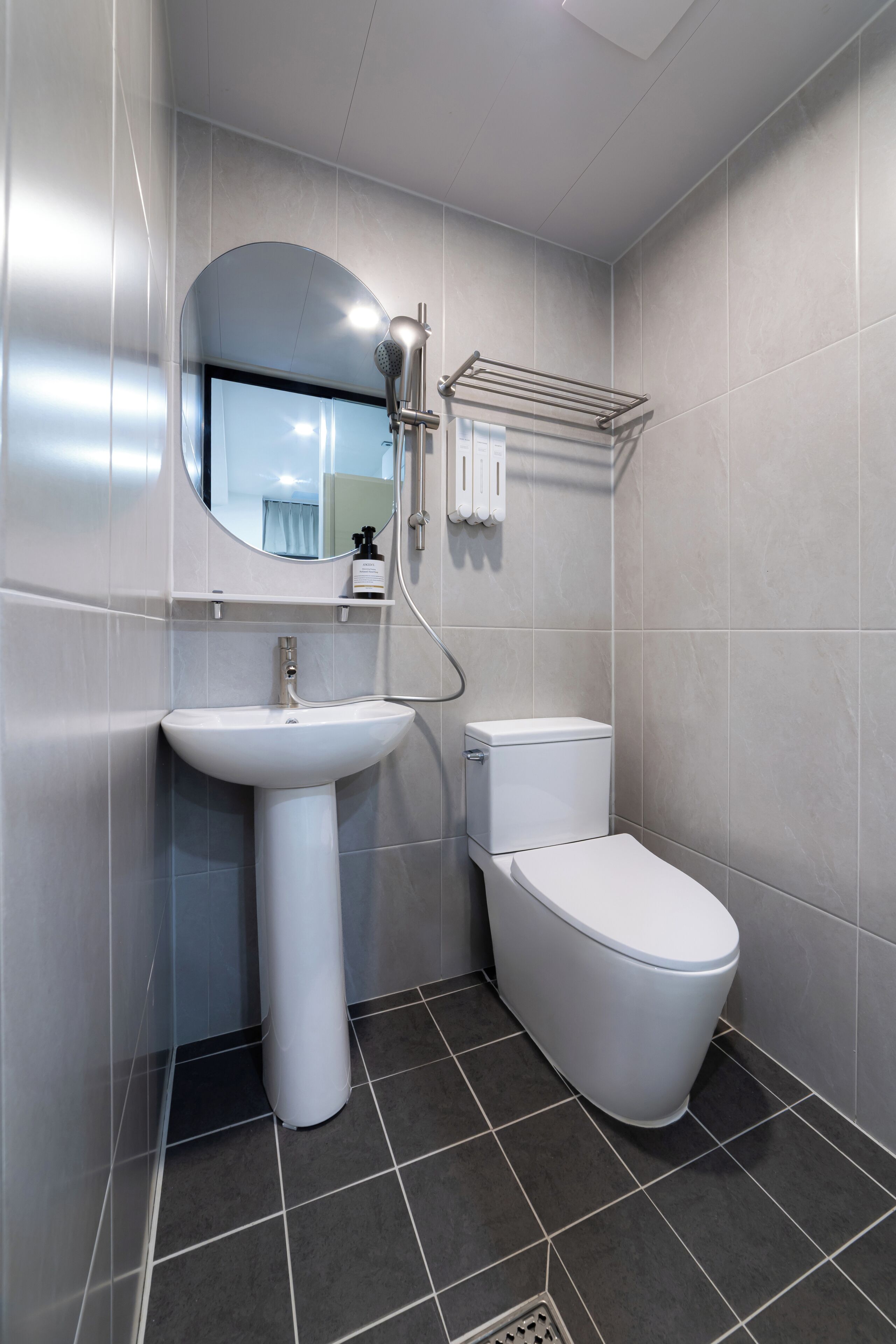 A bathroom with a white sink, toilet, and a mirror with a towel rack.