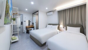 A hotel room with two beds, a desk, a chair, a shelf with a plant, and an air conditioning unit. - Dongdaemun Stay Garden (Seoul)