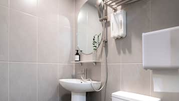 A modern bathroom with a white toilet, pedestal sink, and a towel rack.