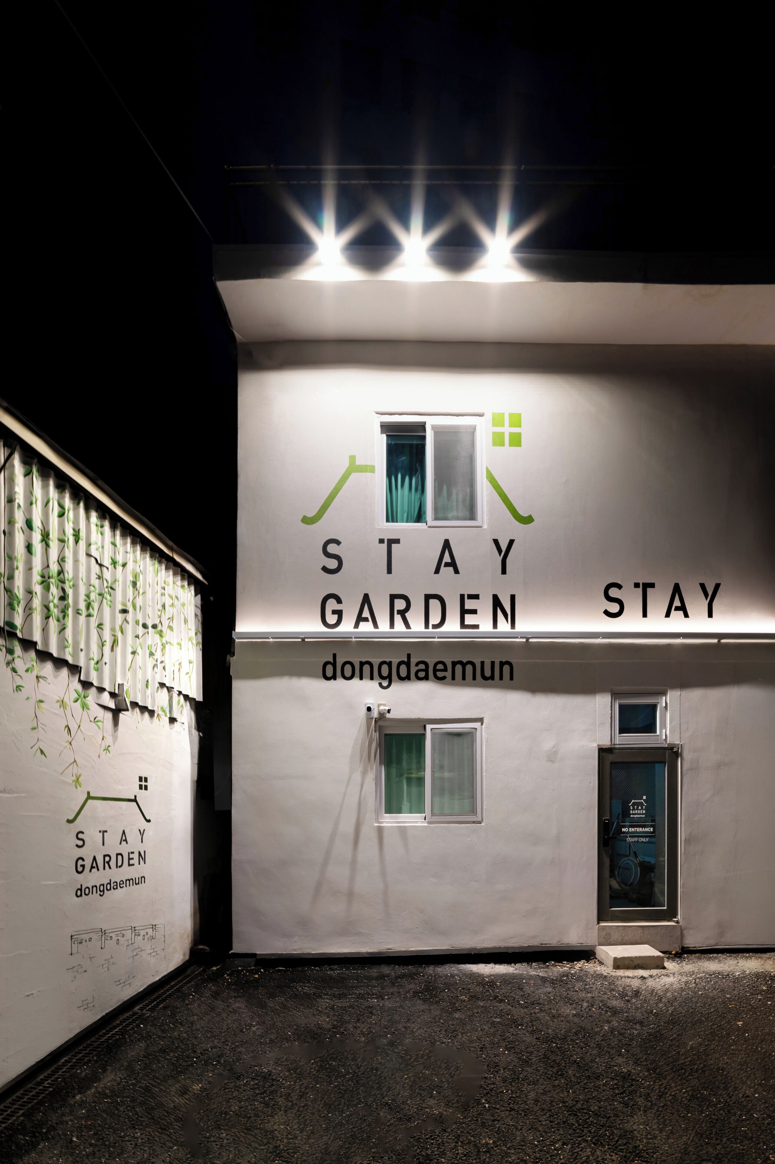 Ein Gebäude mit einem Schild, auf dem 'STAY GARDEN dongdaemun' steht, und einer Tür mit einem Schild, das 'NICHT BETRETEN' anzeigt.