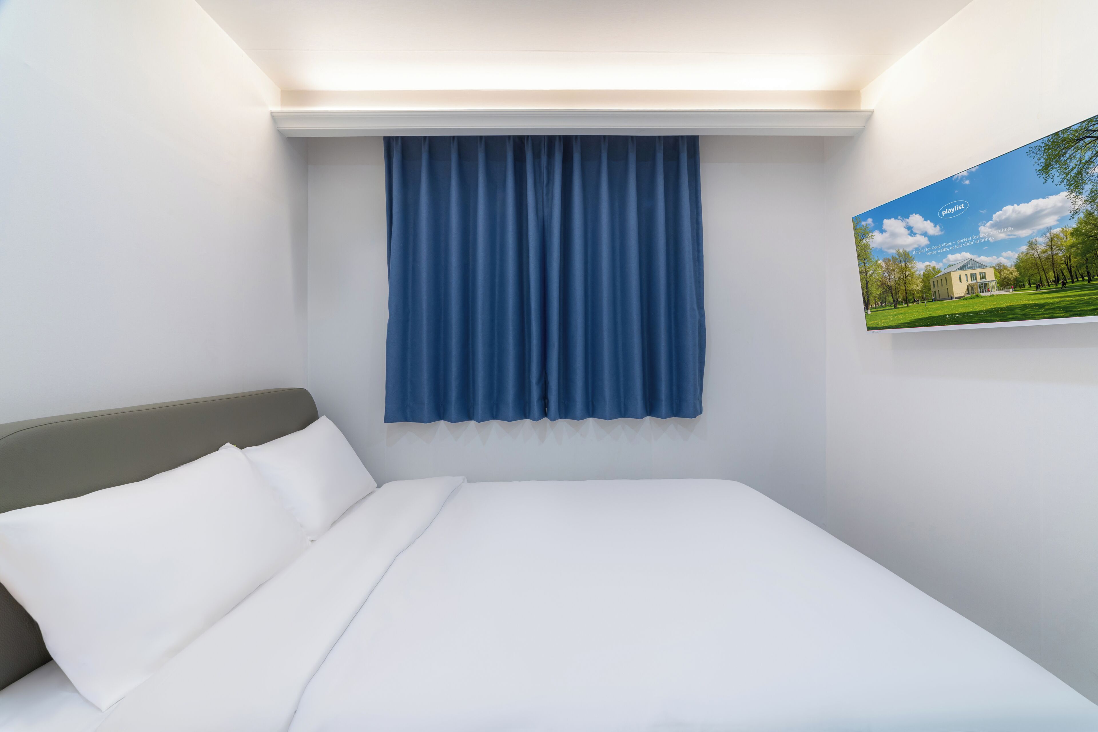 Una habitación de hotel con una cama, una cortina azul y un cuadro en la pared.