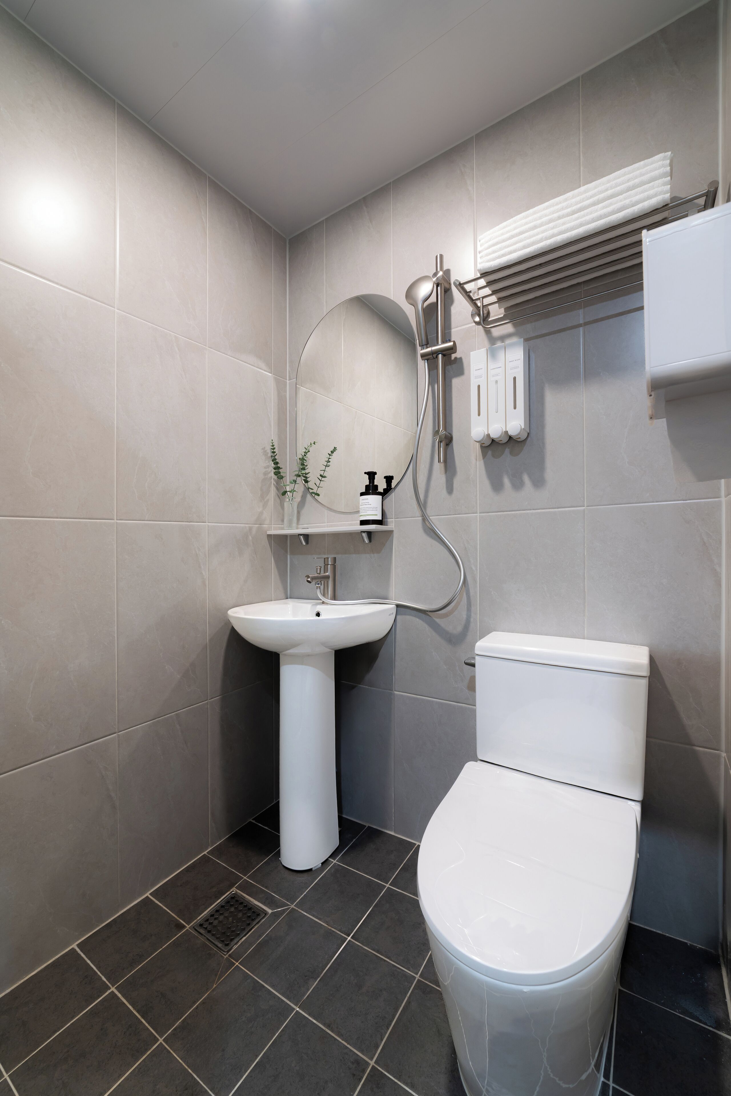 Et moderne badeværelse med toilet, håndvask og et håndklædetørrestativ på væggen.