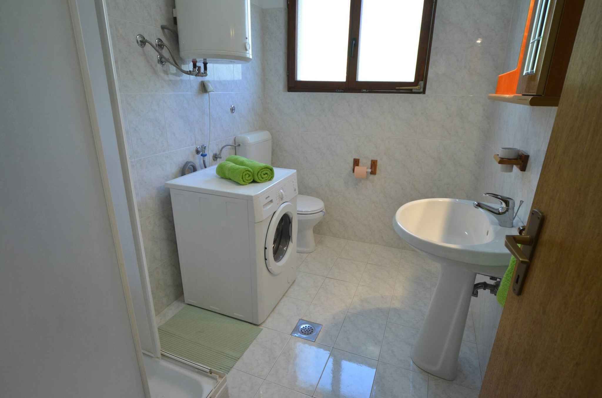Ein kleines Badezimmer mit Waschmaschine, Toilette und Waschbecken.