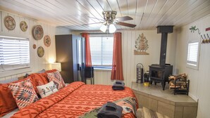 Quarto com cama, ventilador de teto, lareira e janela com cortinas.