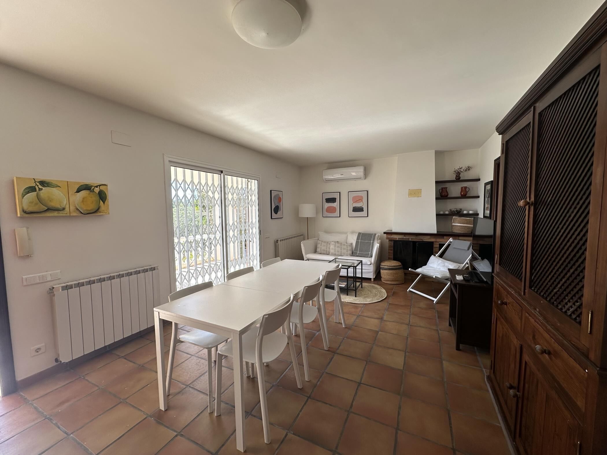 A spacious kitchen with a dining area, white furniture, and a tiled floor.