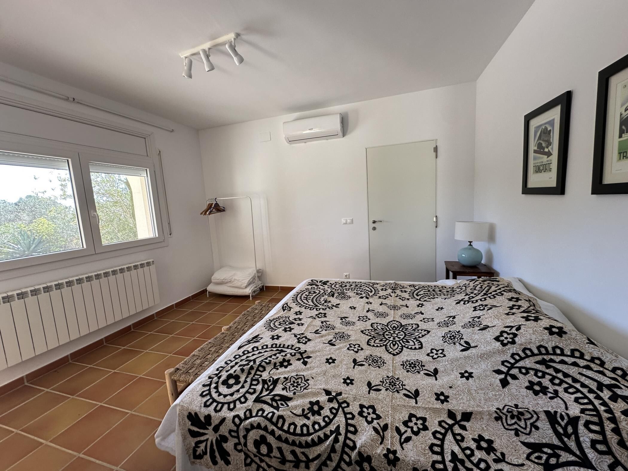 A bedroom with a bed, a radiator, a wardrobe, and a window.