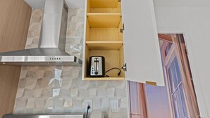 Eine Küche mit eingebautem Toaster, einer Edelstahl-Dunstabzugshaube und einer strukturierten Spritzschutzwand.