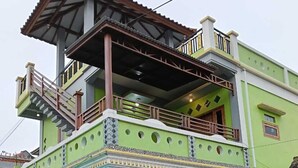 A two-story house with a balcony, a staircase, and a tiled entrance. - Tano Homestay Bromo (Ngadisari)