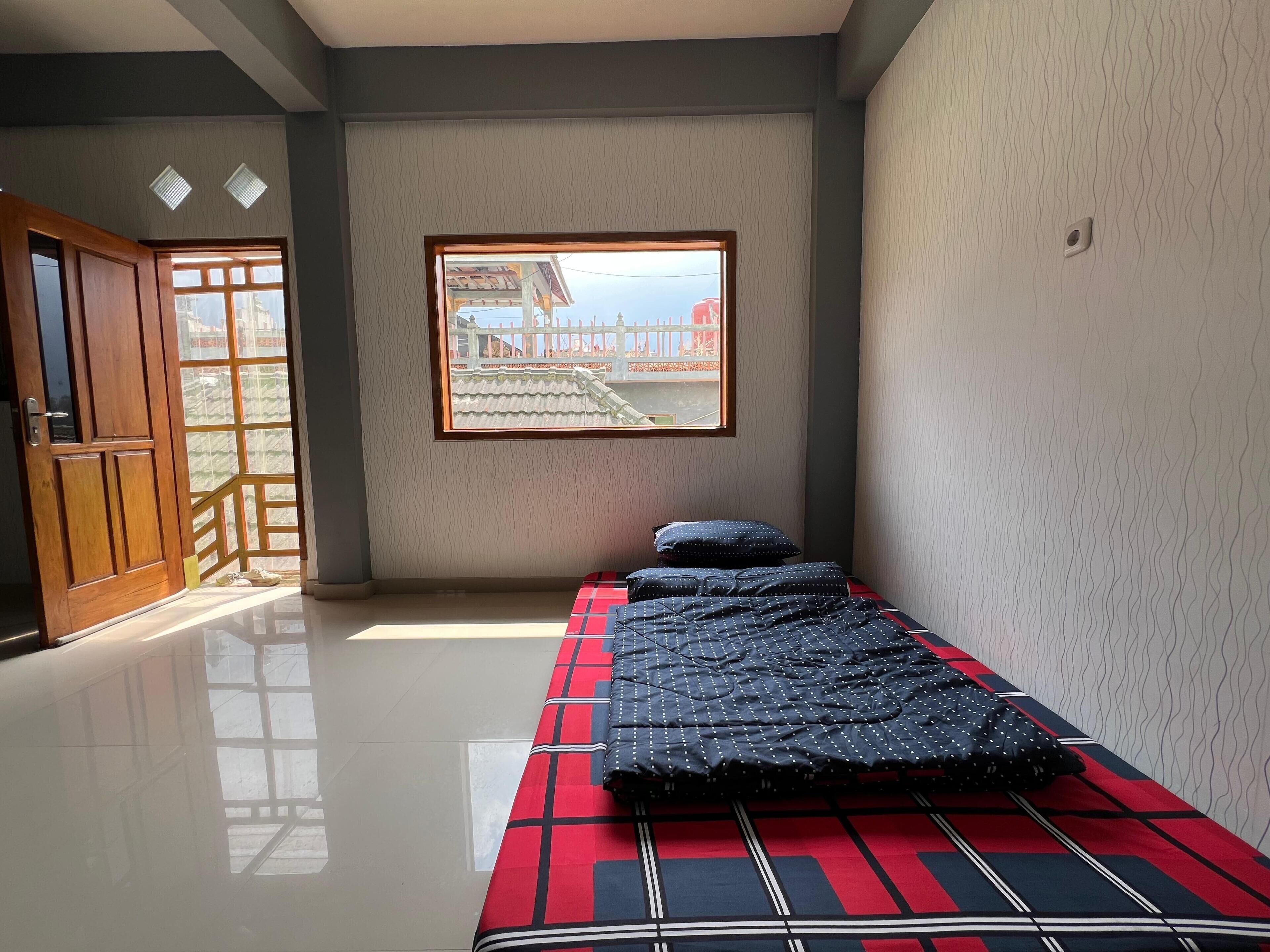 Een kamer met een bed, een raam met uitzicht en een deur.