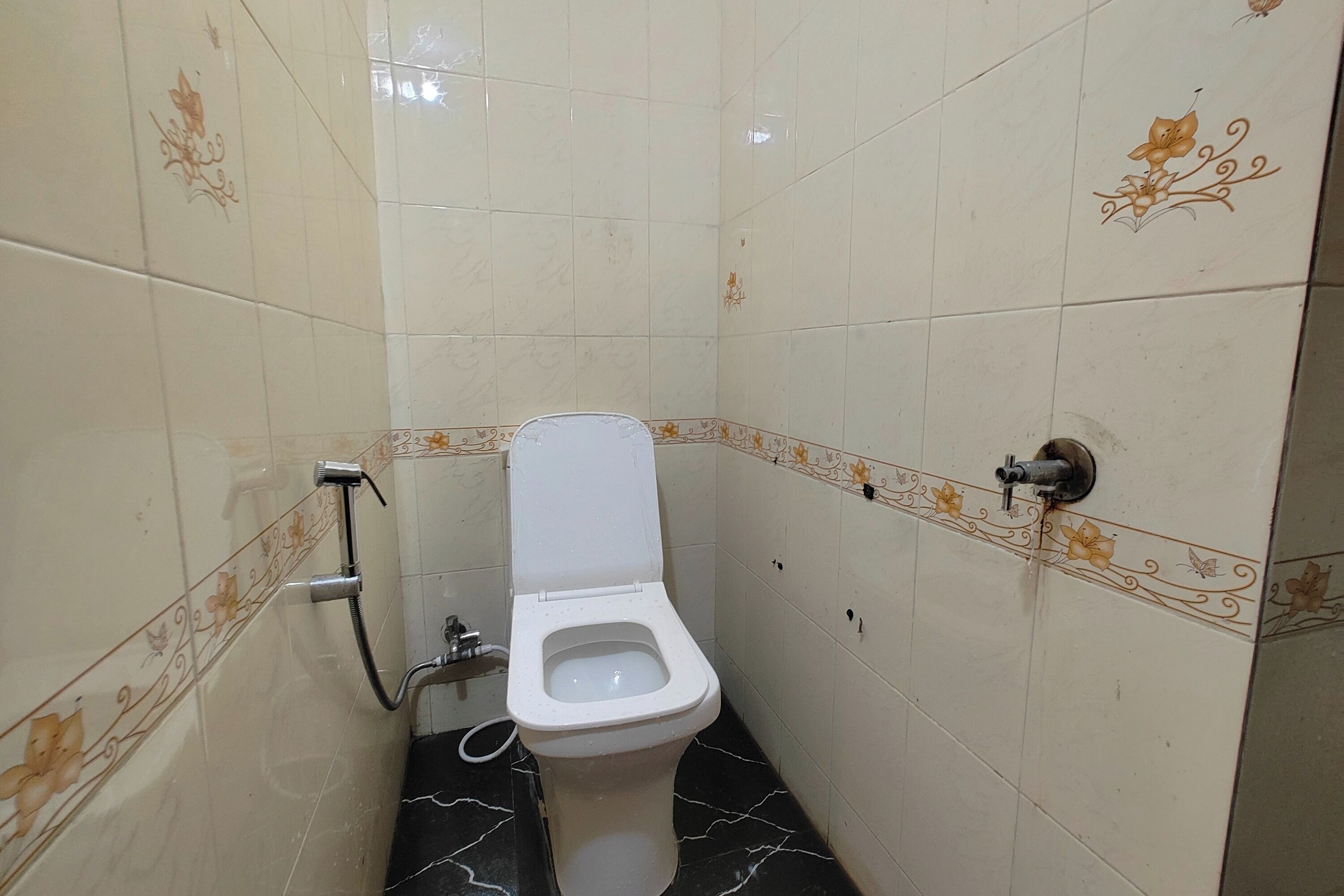 Un bagno piccolo rivestito di piastrelle, con il water, una doccia e un rubinetto a parete.