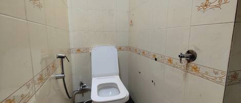 Un bagno piccolo rivestito di piastrelle, con il water, una doccia e un rubinetto a parete.