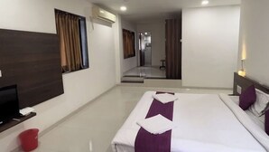 A hotel room with a large bed, a TV, a red bucket, and a mirror. - Saiba Residency (Paud)