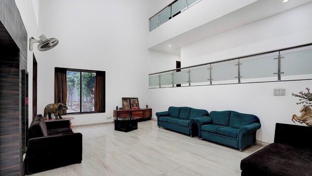 A spacious living room with two sofas, a coffee table, and a decorative statue. - Saiba Residency (Paud)