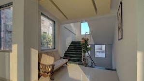 A spacious interior with a staircase, a bench, and a large window. - Saiba Residency (Paud)