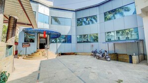 A modern building with a curved facade, large windows, and a covered entrance area with steps leading up to it. - Saiba Residency (Paud)