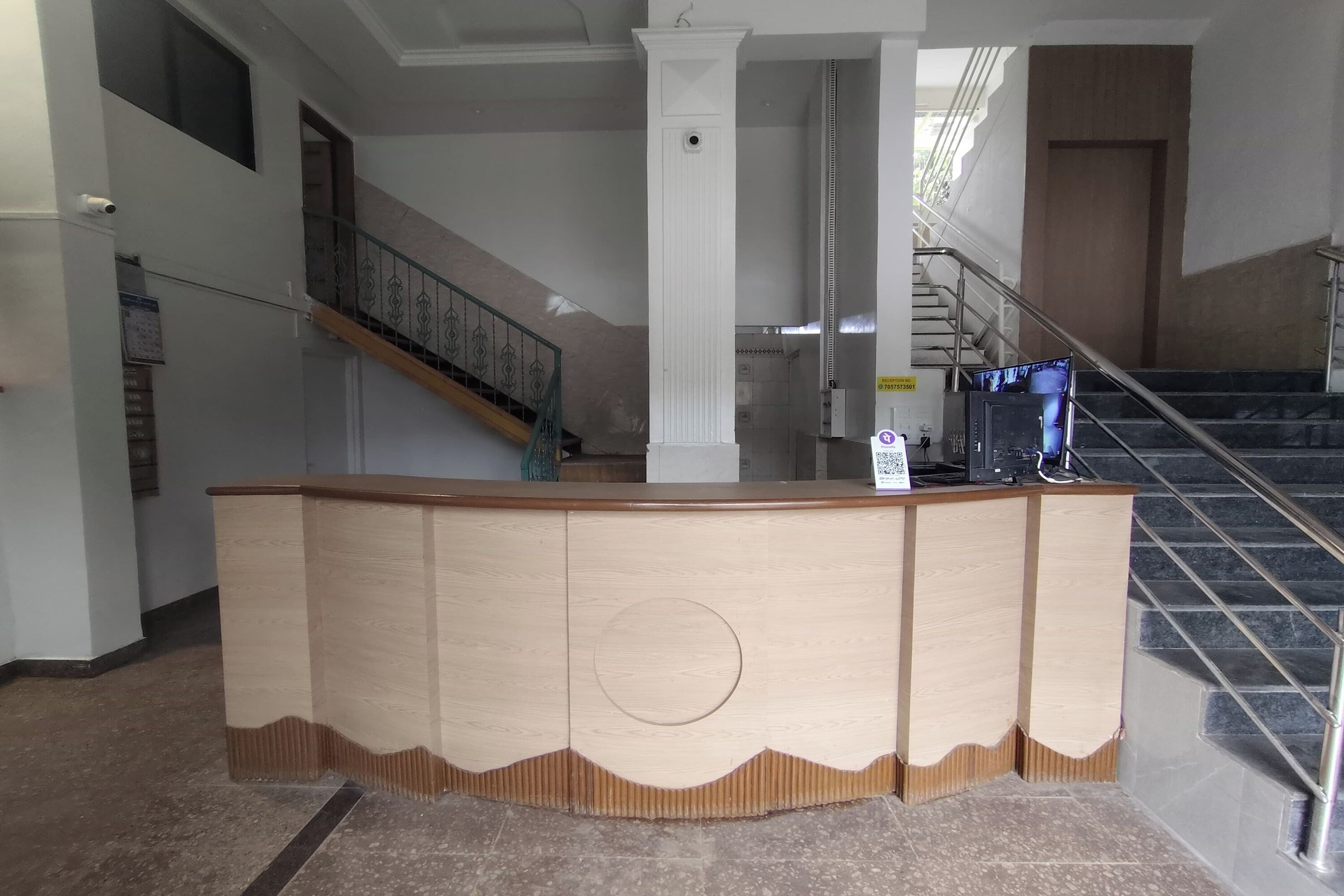 A reception desk in a lobby with a staircase and a door in the background.
