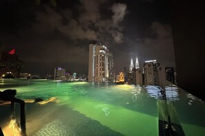Una vista notturna di una città con edifici illuminati e una piscina con luci verdi.