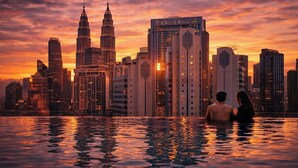 Une vue sur la ville avec les tours Petronas et un immeuble argenté, un couple dans une piscine et un coucher de soleil.