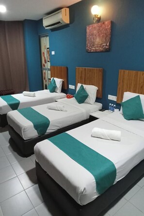 A hotel room with three single beds, each with a white and green bedspread, a wooden headboard, and a wall-mounted air conditioner. -  Sun Tree Hotel @ Triang (Teriang)