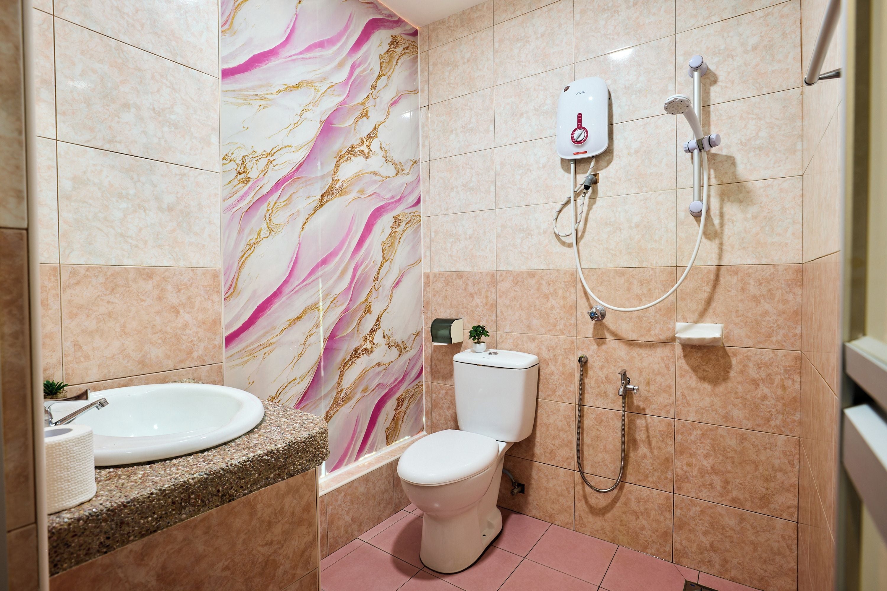 Un baño con pared de mármol, inodoro, lavamanos y ducha.