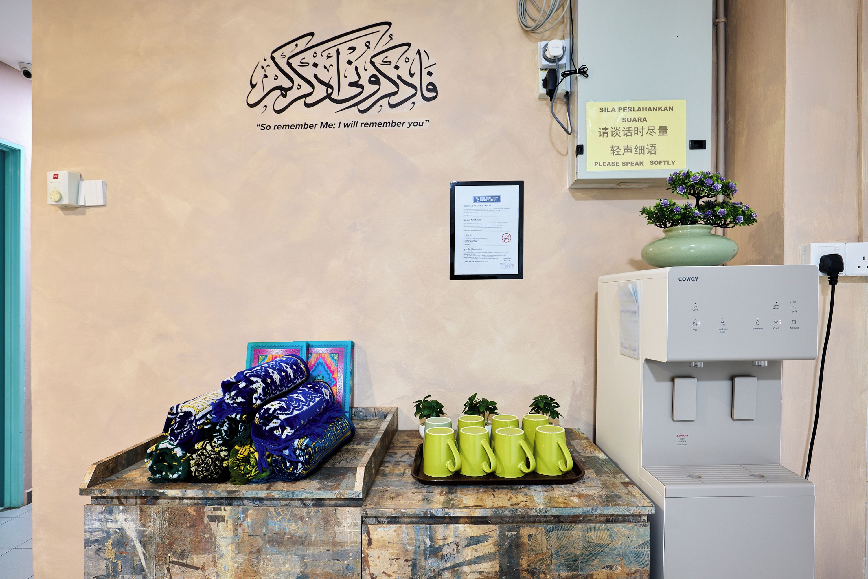 A reception area with a wall-mounted sign, a water station, and a display of colorful scarves.