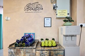 Zona de recepción con un letrero en la pared, una estación de agua y una exhibición de pañuelos de colores.