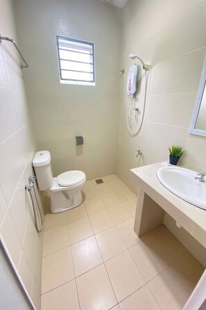 A small, clean bathroom with a toilet, a sink, a shower, and a small window. -  Sun Tree Hotel @ Triang (Teriang)