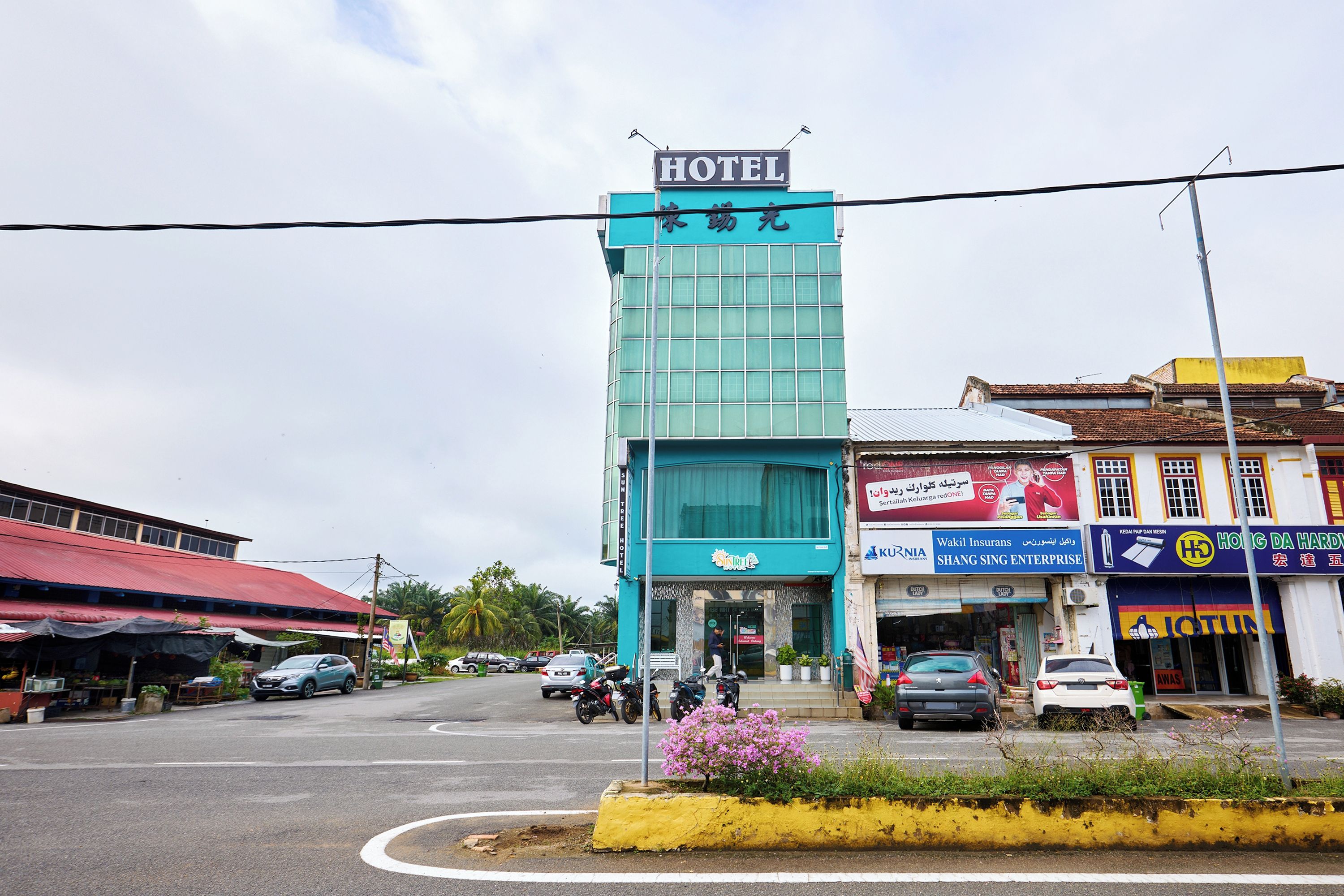 A hotel with a modern glass facade, a visible entrance, and a parking lot with several cars.