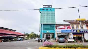 A hotel with a modern glass facade, a visible entrance, and a parking lot with several cars.