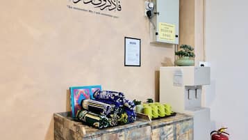 A reception area with a water station sign, a framed notice, a potted plant, and a fire extinguisher.