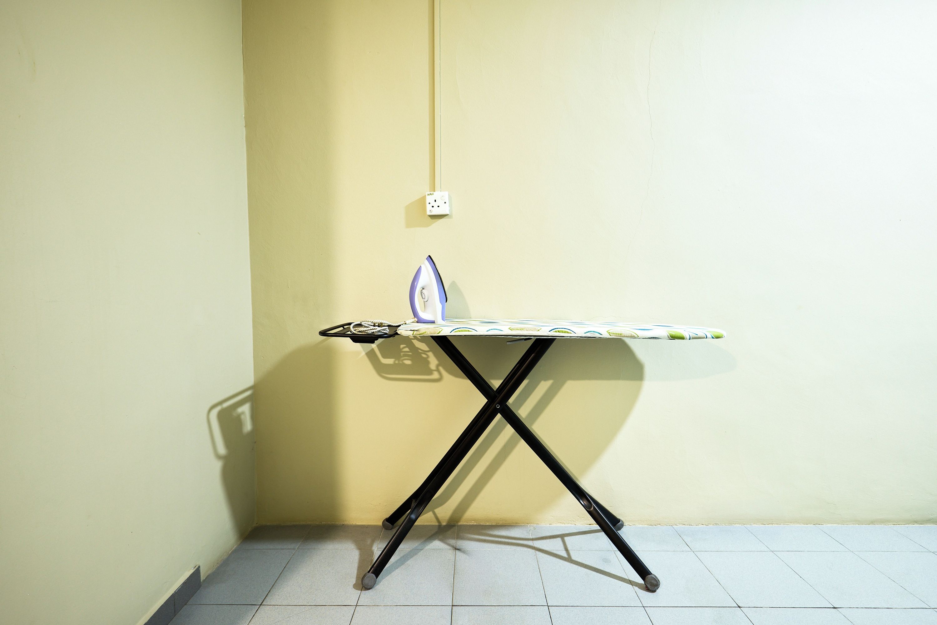 A corner room with a wall-mounted ironing board and a power outlet.
