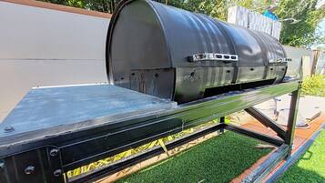 A barbecue grill with a metal frame and a curved top, placed on a flat surface outdoors.
